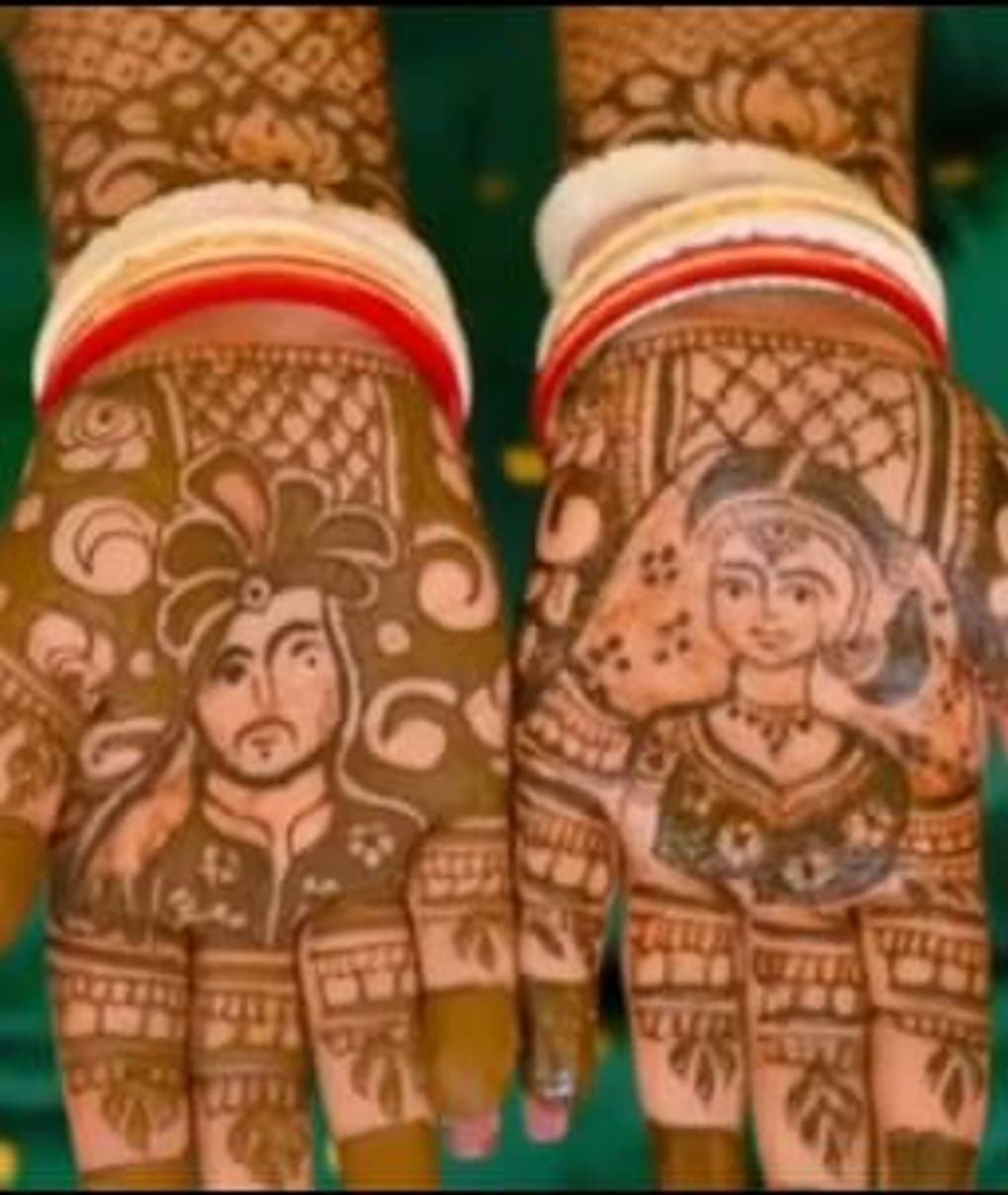 A bride's two palms covered in intricate bridal mehndi, each painted with a portrait of the bride and groom