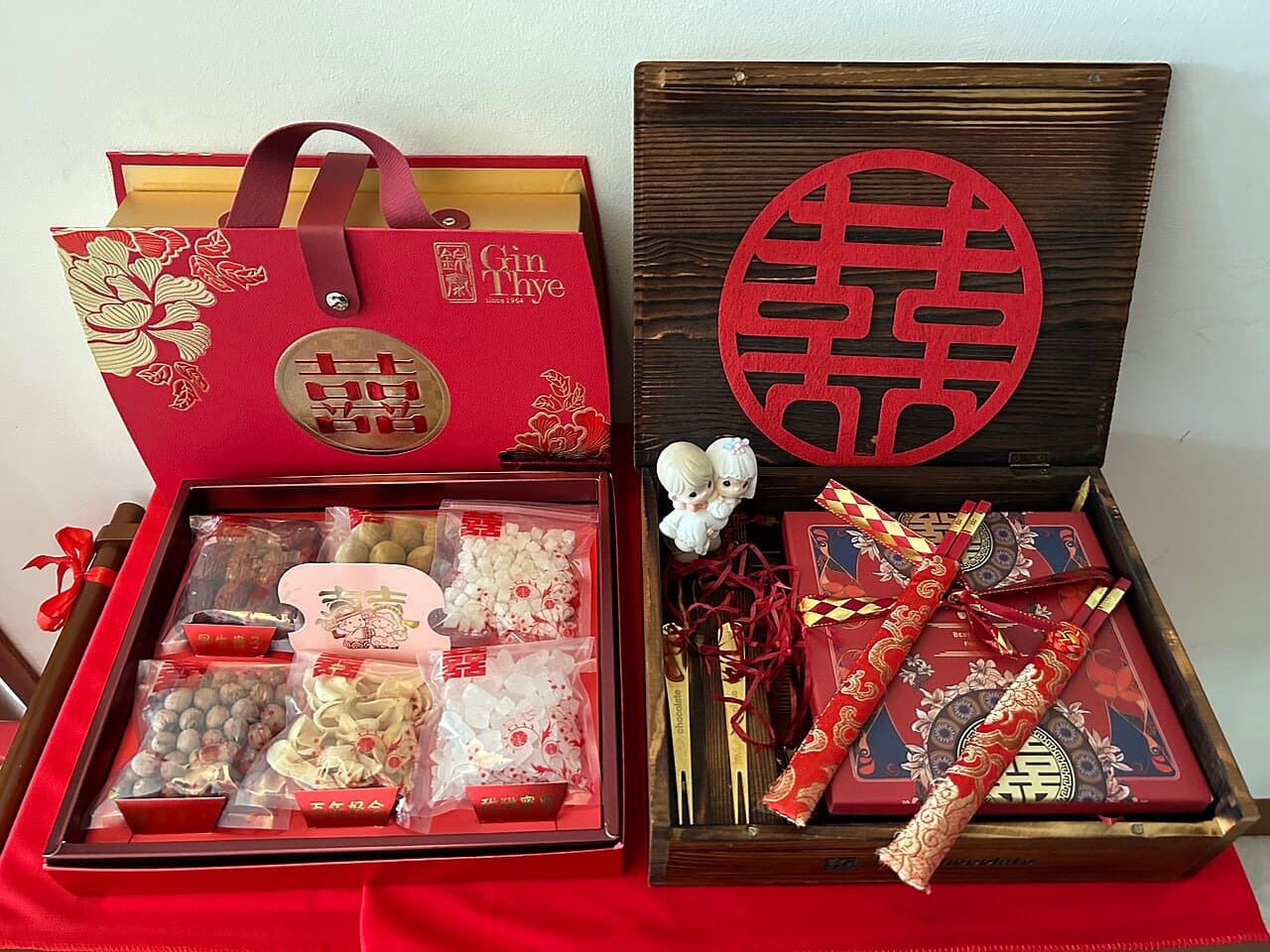 A Chinese betrothal (guo da li) gift set — red and dark-wood boxes with the double-happiness symbol, dried delicacies and dragon-phoenix chopsticks